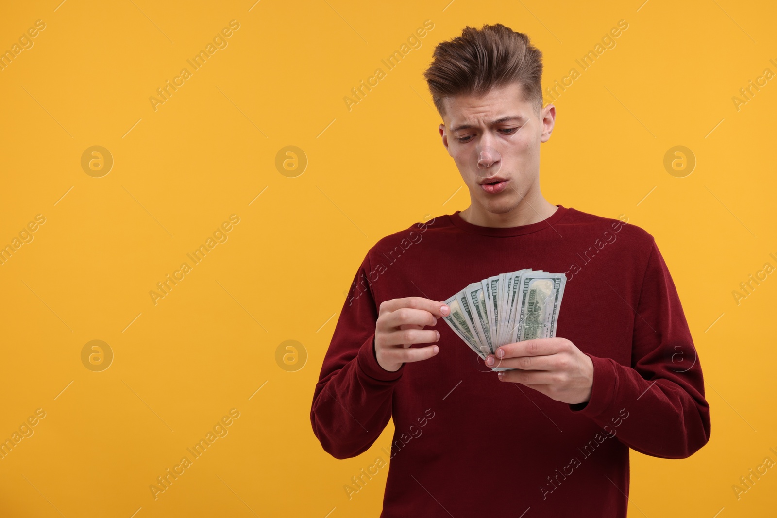 Photo of Handsome man with dollar banknotes on yellow background. Space for text