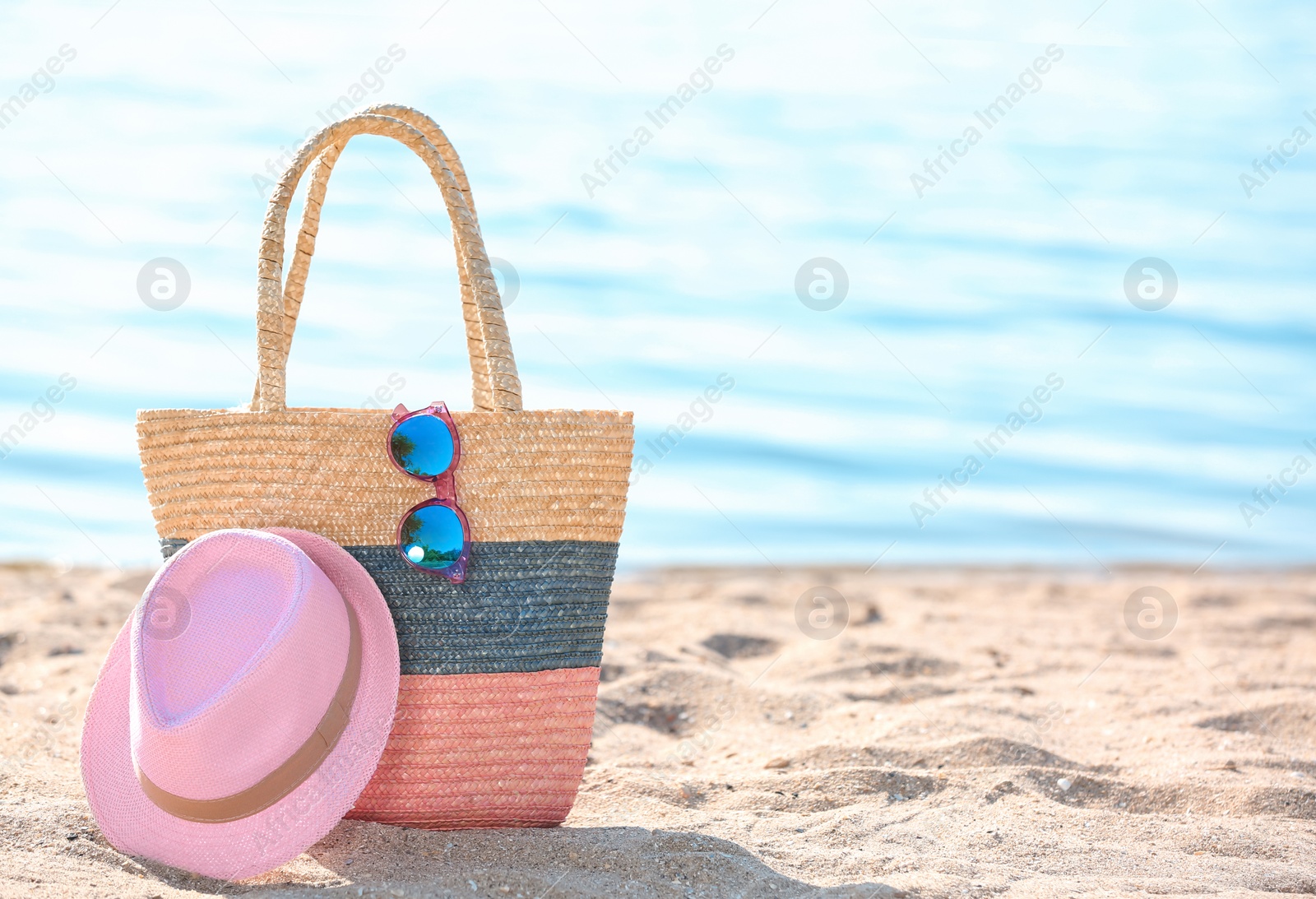 Photo of Bag, sunglasses and hat on sand near sea. Beach object