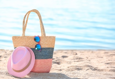 Photo of Bag, sunglasses and hat on sand near sea. Beach object