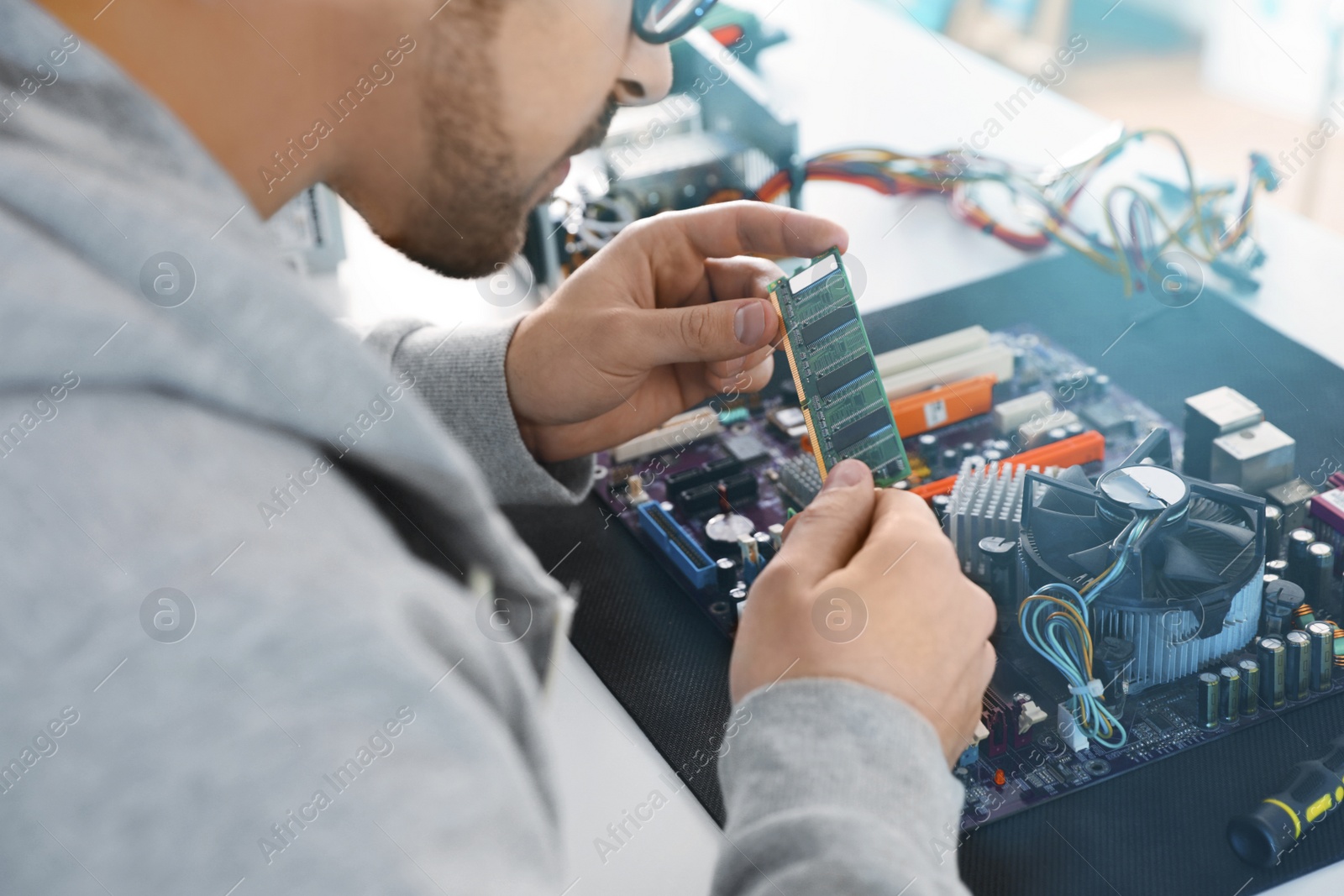 Photo of Male technician repairing motherboard at table, closeup