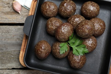 Tasty cooked meatballs with parsley on wooden table, flat lay