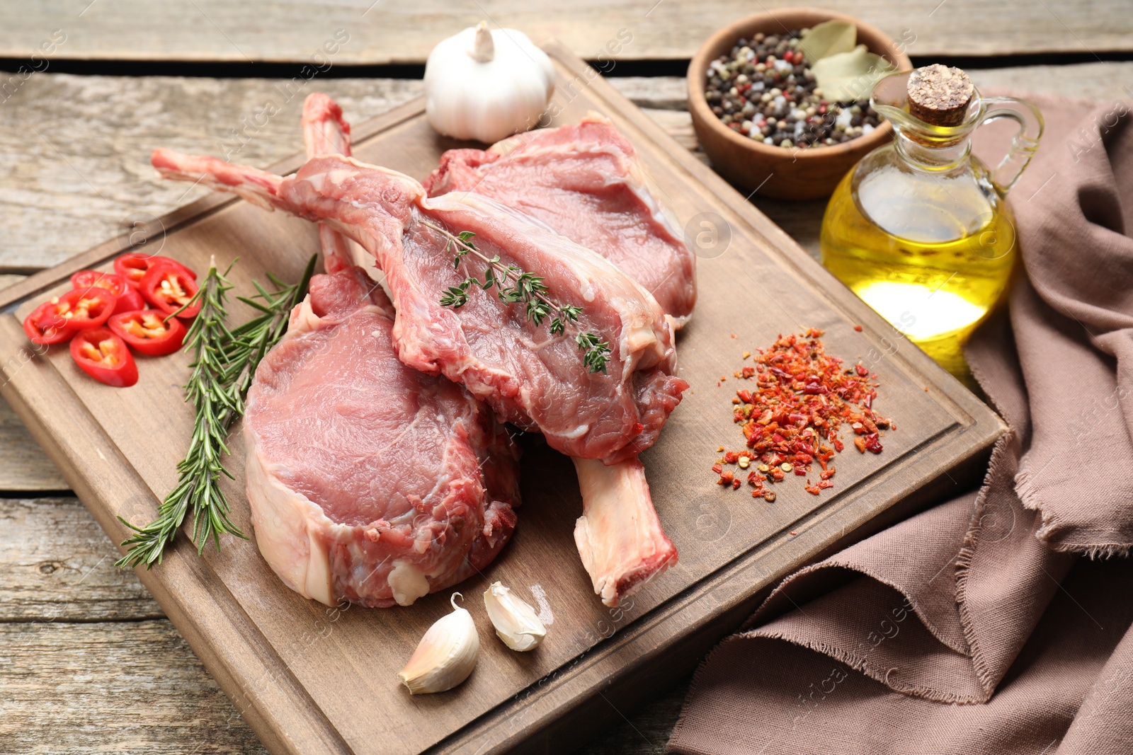 Photo of Fresh tomahawk beef cuts and spices on wooden table