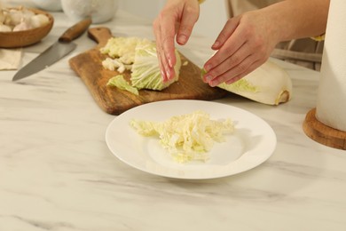 Photo of Woman with cut Chinese cabbage at white kitchen table, closeup