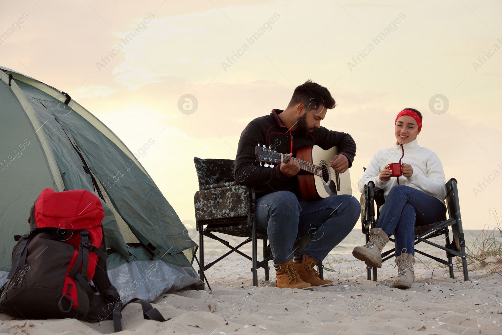 Photo of Lovely couple resting near camping tent on sandy beach