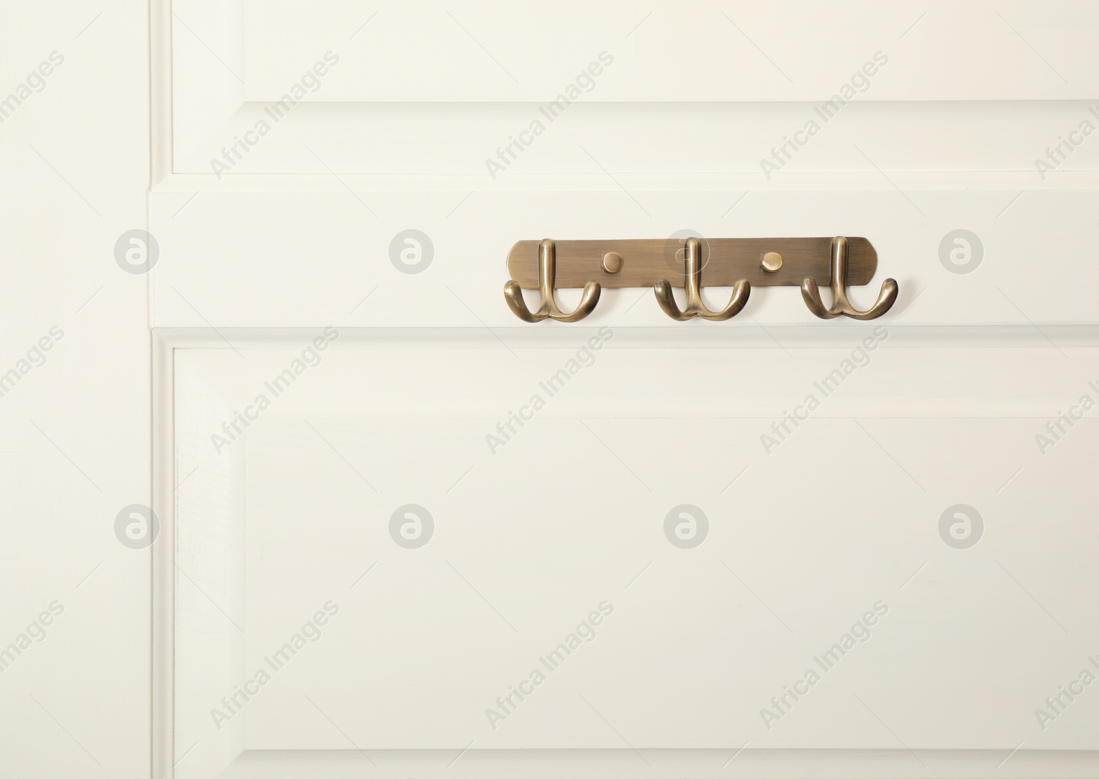 Photo of White door with empty metal clothes hooks