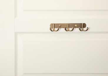 Photo of White door with empty metal clothes hooks
