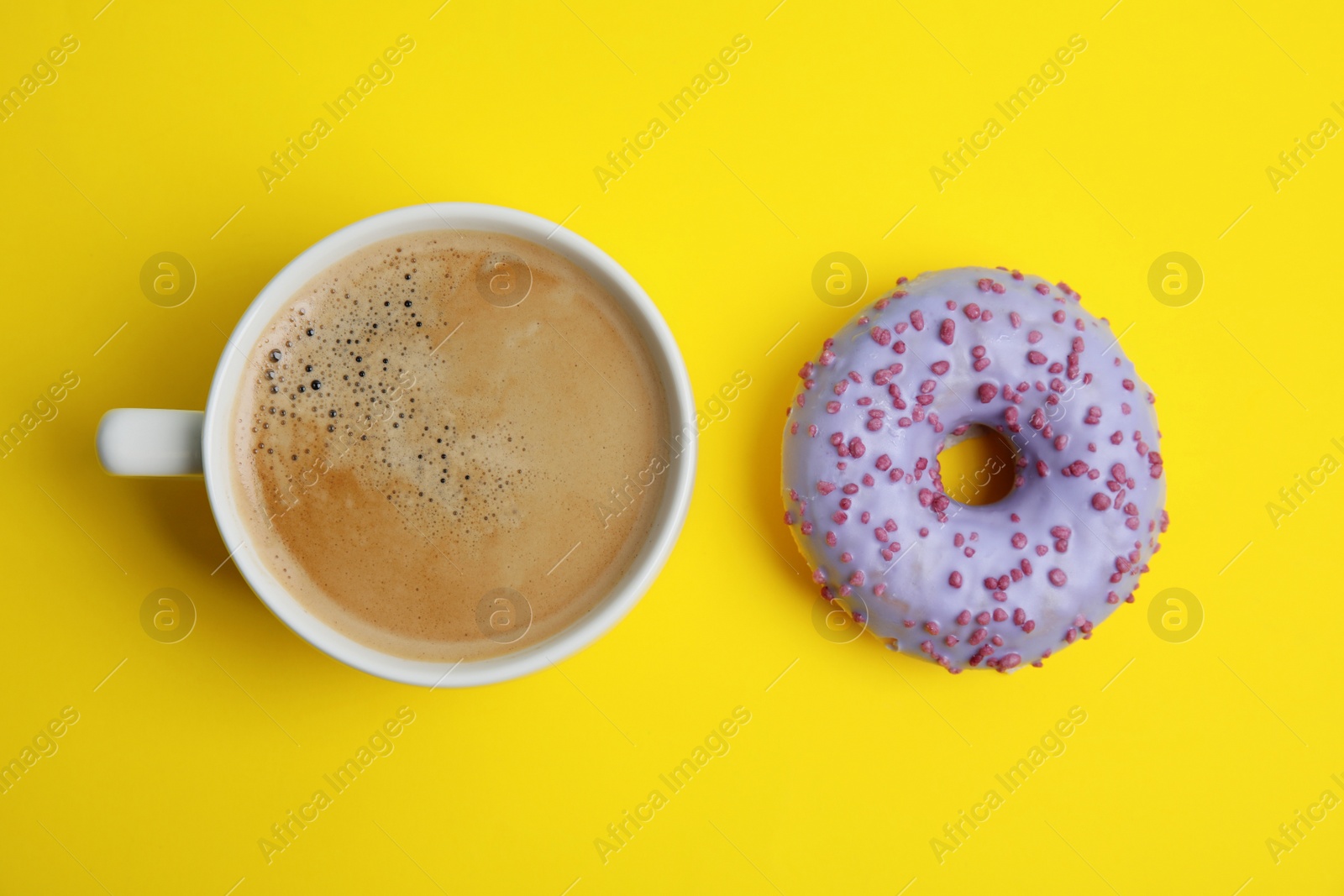 Photo of Delicious coffee and donut on yellow background, flat lay. Sweet pastries