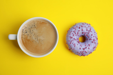 Photo of Delicious coffee and donut on yellow background, flat lay. Sweet pastries