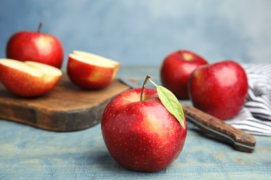 Photo of Ripe juicy red apples on wooden table against blue background. Space for text