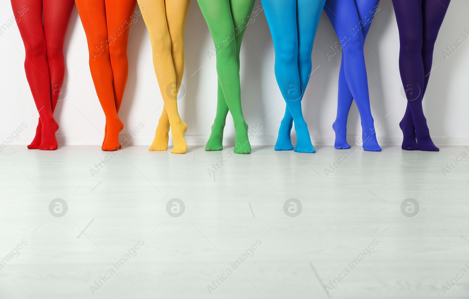 Photo of Women wearing colorful tights near white wall, closeup