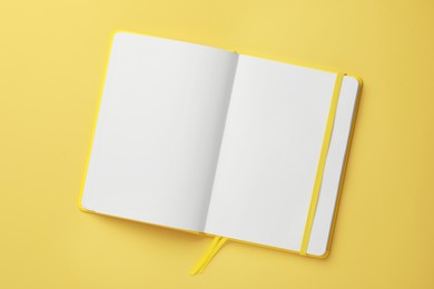 Photo of Blank notebook on pale yellow background, top view