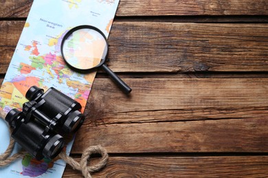 Photo of Modern binoculars, magnifying glass, map and rope on wooden table, flat lay. Space for text