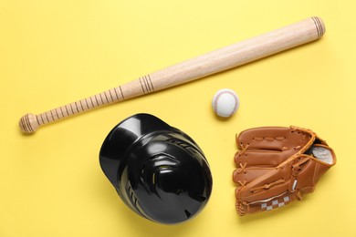 Baseball glove, bat, ball and batting helmet on yellow background, flat lay