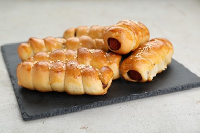 Serving board with delicious sausage rolls on beige table, closeup
