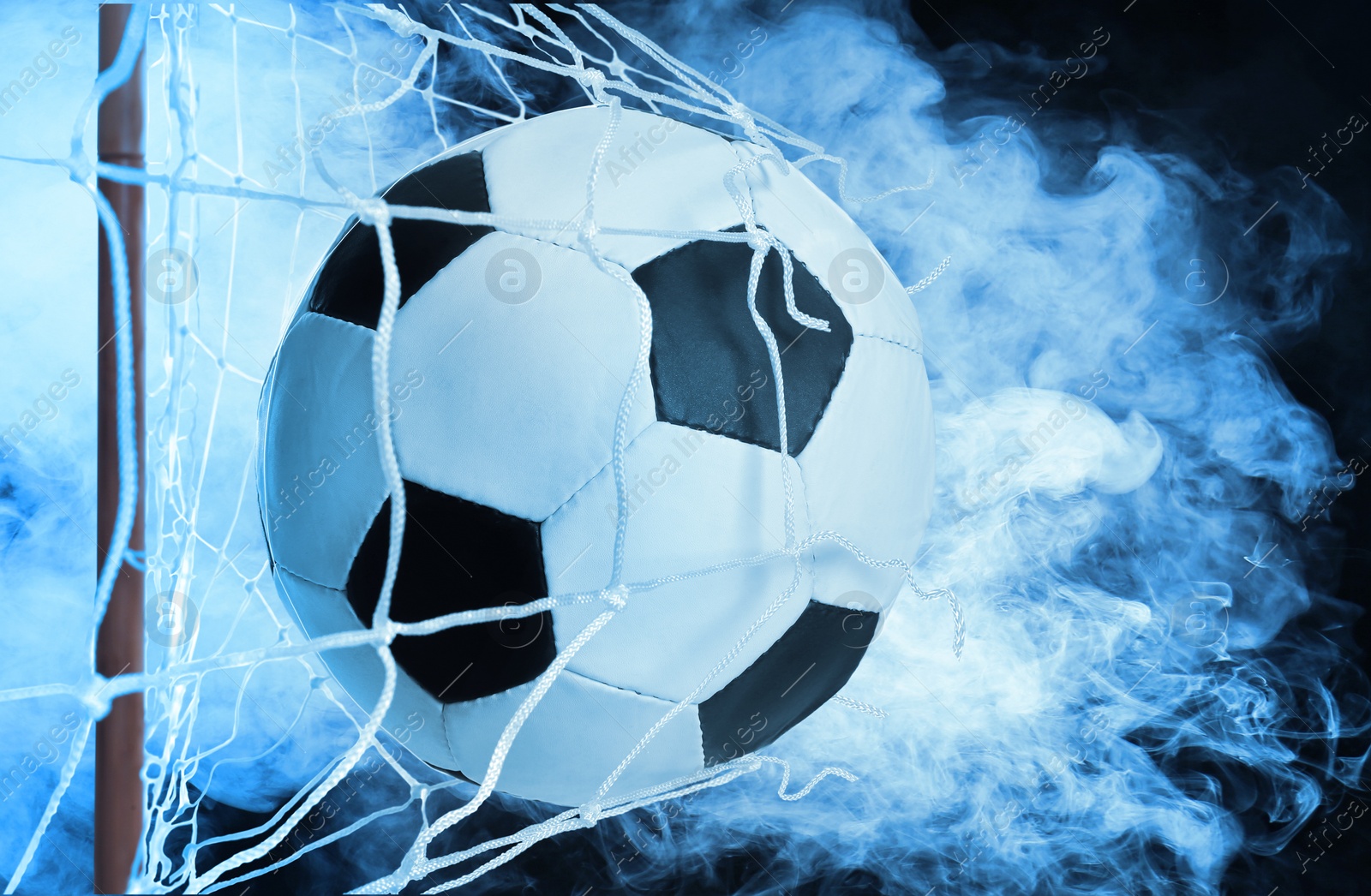 Image of Soccer ball in net and white smoke against black background
