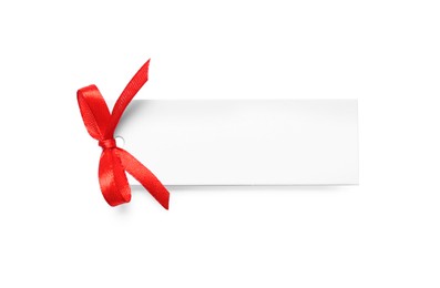 Photo of Blank gift tag with red satin ribbon on white background, top view. Space for design