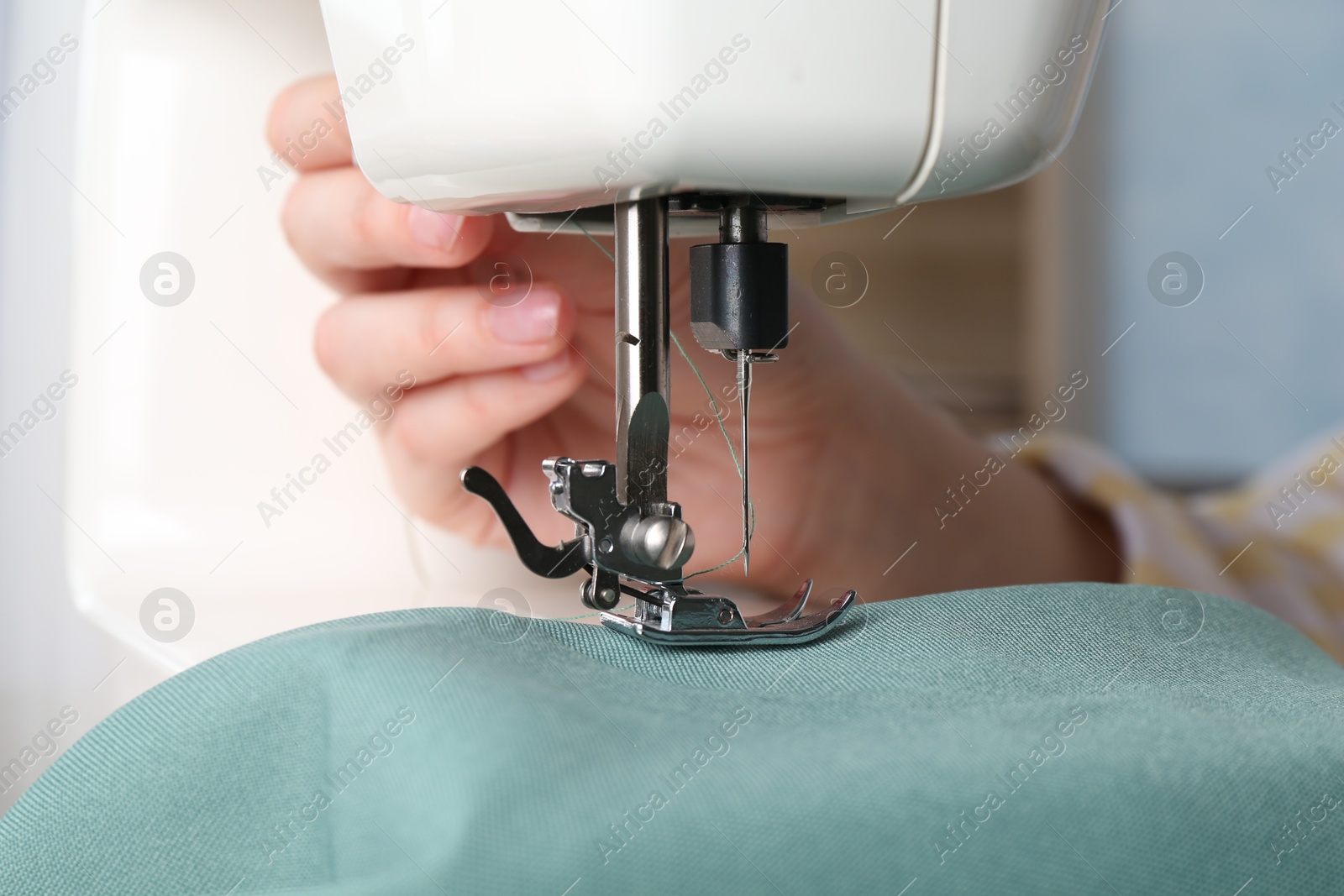 Photo of Seamstress working with sewing machine indoors, closeup