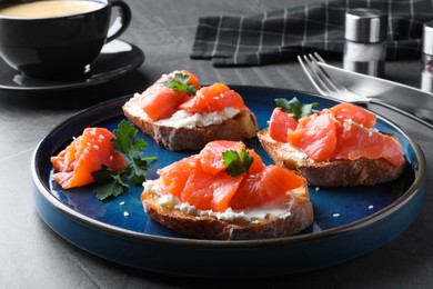 Photo of Tasty bruschettas with salmon, cream cheese and parsley on grey table