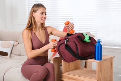 Photo of Woman packing sports stuff for training into bag at home