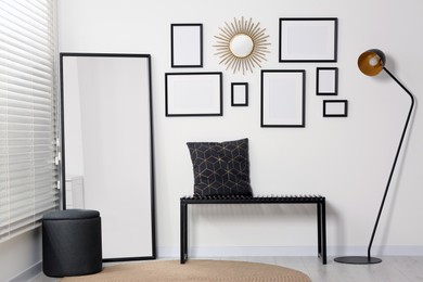 Photo of Stylish room interior with empty frames hanging on white wall and comfortable furniture