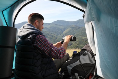 Photo of Man with thermos inside of camping tent in mountains