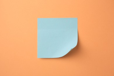 Photo of Blank paper note on pale orange background, top view