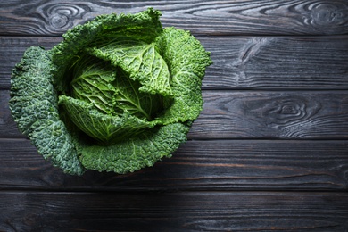 Photo of Fresh ripe savoy cabbage on black wooden table, top view. Space for text