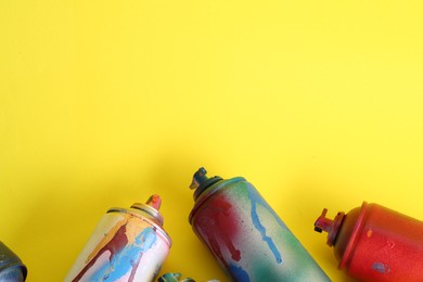 Photo of Many spray paint cans on yellow background, space for text