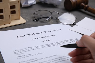 Photo of Woman signing last will and testament at grey table, closeup