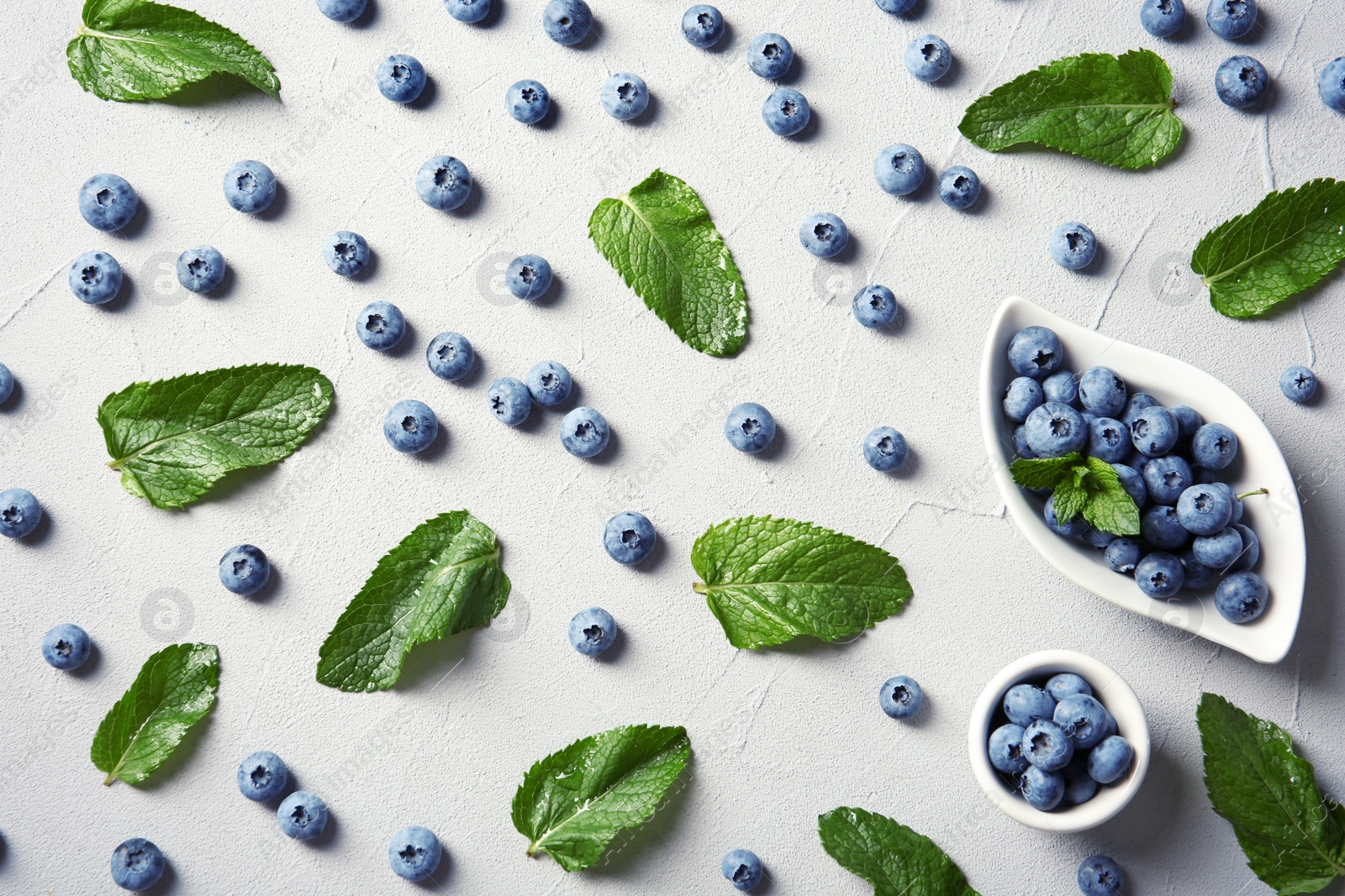 Photo of Flat lay composition with juicy blueberries and green leaves on color table
