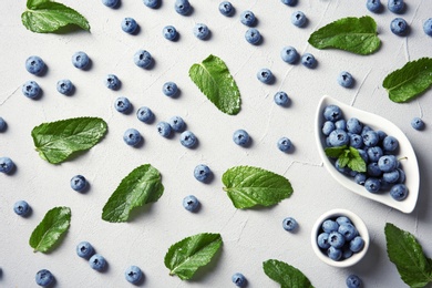 Flat lay composition with juicy blueberries and green leaves on color table