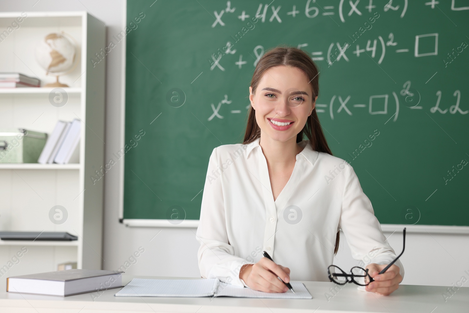 Photo of Young math’s teacher giving lesson at table in classroom