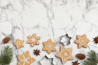 Tasty Christmas cookies, cutters and fir branches on white marble table, flat lay. Space for text