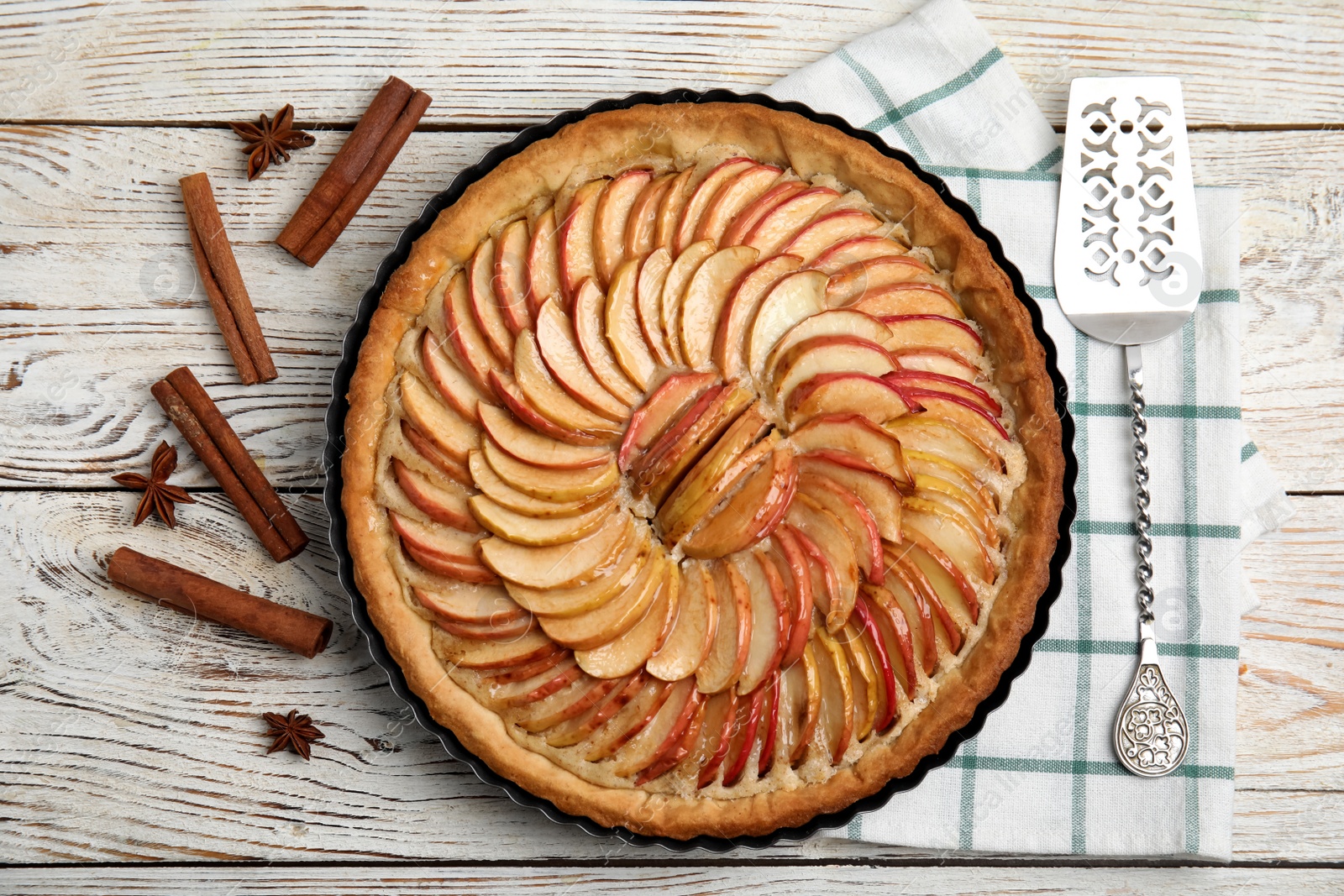 Photo of Delicious homemade apple tart, cinnamon, anise and cake shovel on white wooden table, flat lay
