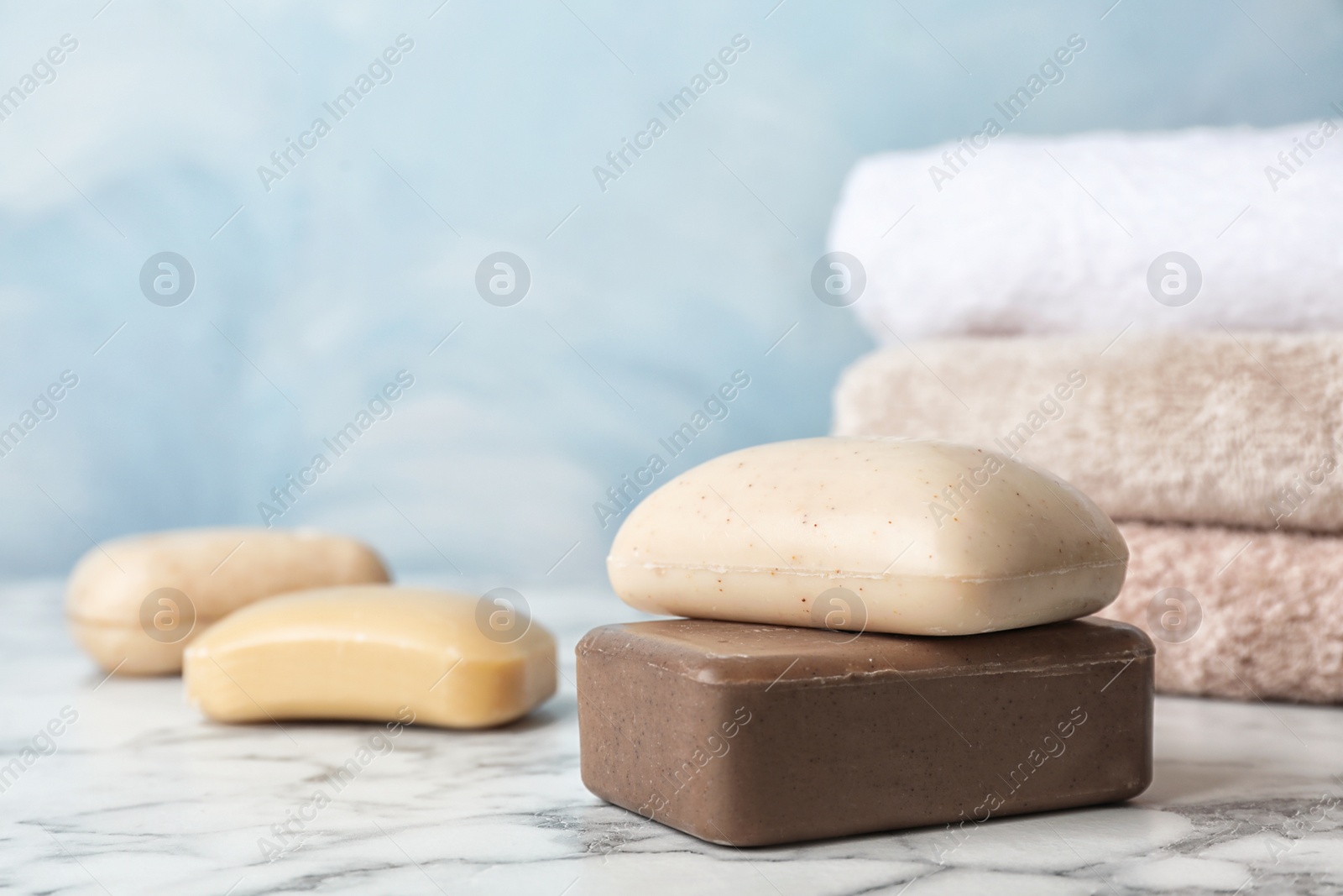Photo of Different soap bars on marble table against color background. Space for text