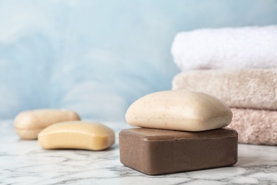 Different soap bars on marble table against color background. Space for text