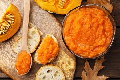 Photo of Slices of bread with delicious pumpkin jam and fresh pumpkin on wooden table, flat lay