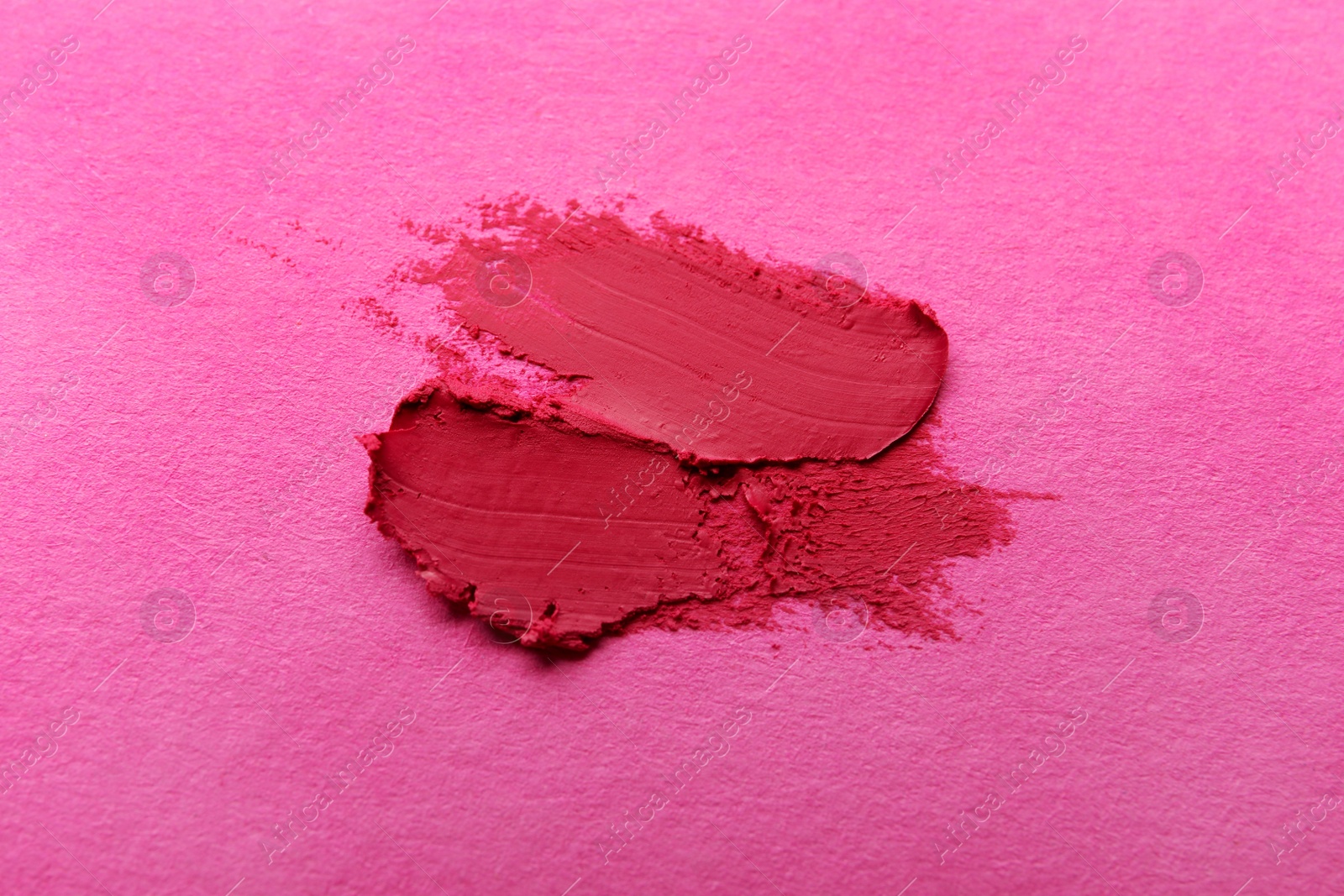 Photo of Smears of beautiful lipstick on pink background, top view