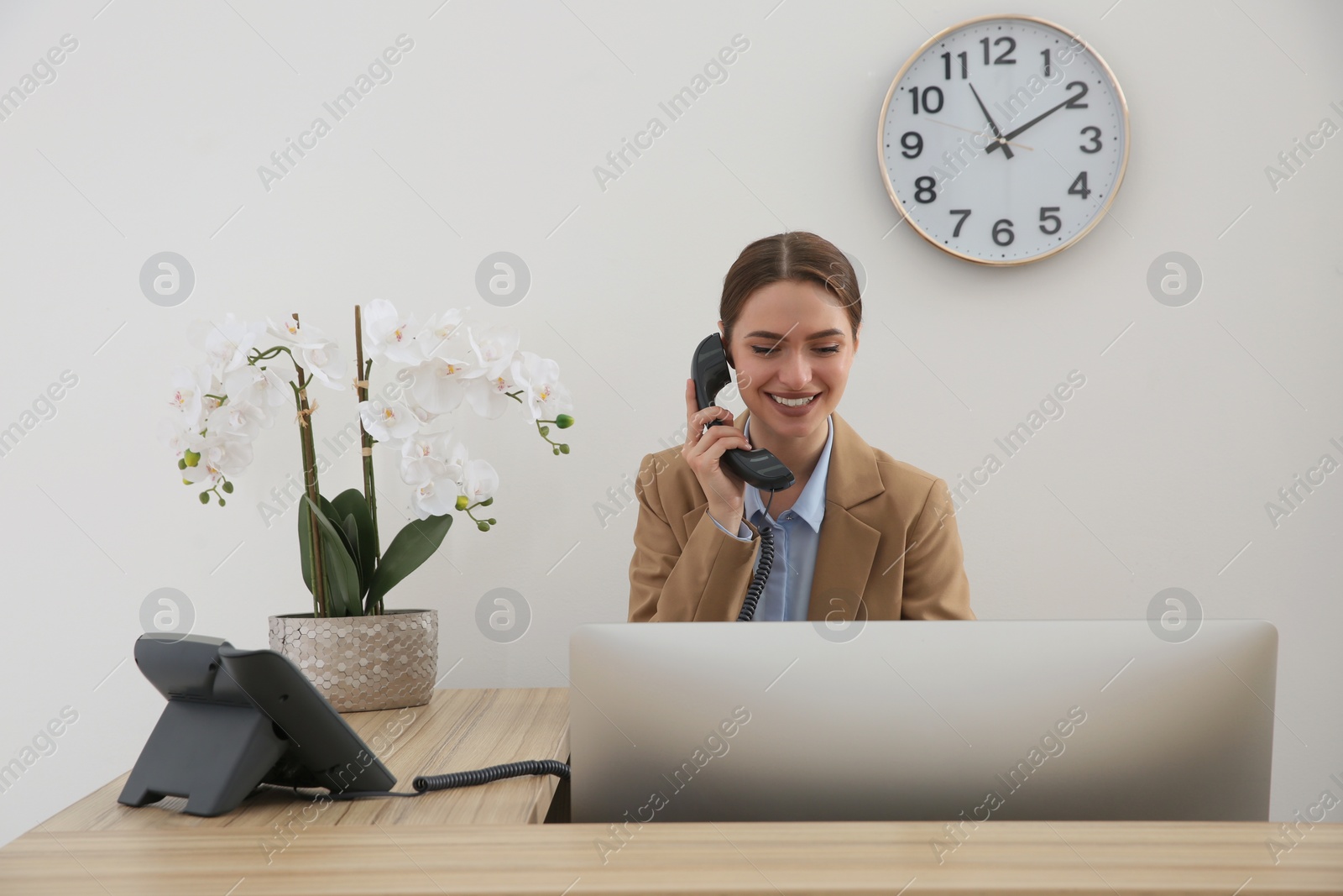 Photo of Beautiful receptionist talking on phone at counter in hotel