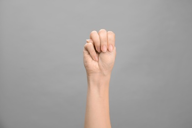 Photo of Woman showing M letter on grey background, closeup. Sign language
