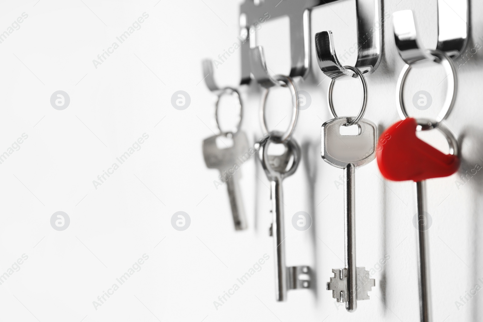 Photo of Metal key holder on light wall indoors, closeup. Space for text
