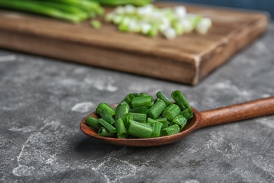 Photo of Spoon with chopped green onion on table