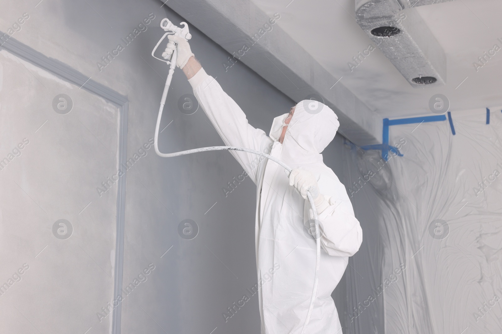 Photo of Decorator dyeing wall in grey color with spray paint indoors