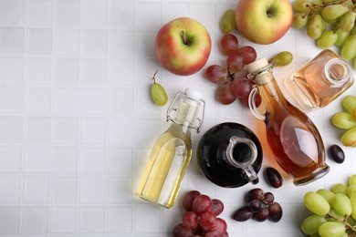 Photo of Different types of vinegar and ingredients on light tiled table, flat lay. Space for text