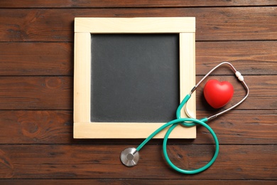 Photo of Stethoscope, heart and blackboard with space for text on wooden background, top view. Cardiology concept