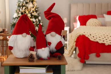 Cute Christmas gnomes on wooden table in room with festive decorations
