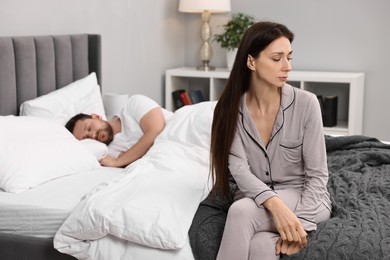 Photo of Stressed wife after quarrel with her husband sitting on bed, selective focus. Relationship problems