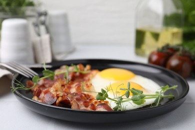 Fried eggs and bacon served on white table, closeup