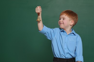 Photo of Pupil with school bell near green chalkboard. Space for text