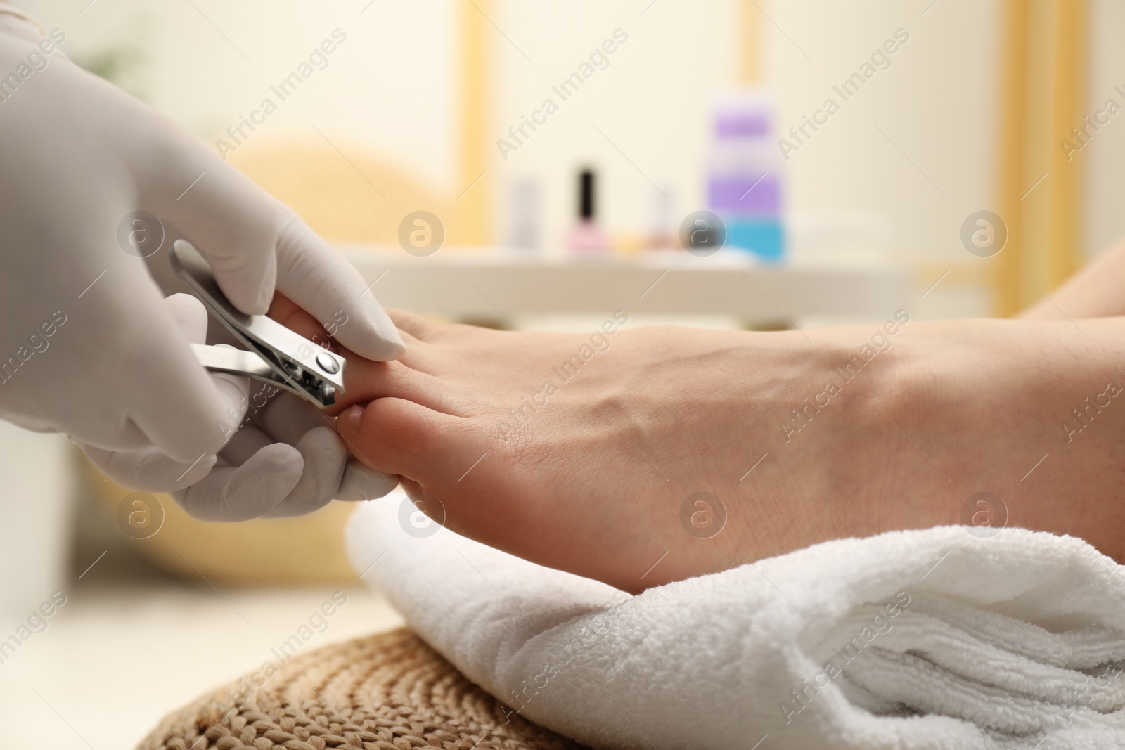 Photo of Professional pedicurist cutting client`s toenails with clipper in beauty salon, closeup